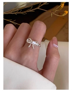 Close-up of a silver bow ring on a finger with a delicate and minimalist aesthetic