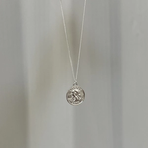 Minimalist vintage silver coin necklace with embossed queen portrait on gray fabric