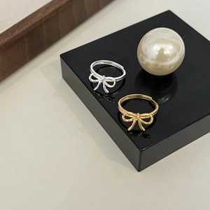 Detail of adjustable bow rings in silver and gold tones on a premium display stand