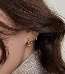 Close-up of gold geometric twist stud earrings and beaded ear cuffs on female model