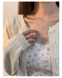 Détail du collier croissant en argent S925 sur mannequin avec gilet beige
