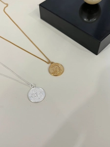 Detail of vintage gold and silver coin pendants with intricate embossed Liberty portrait