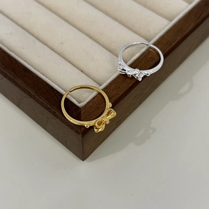 Anelli a fiocco regolabili in oro e argento presentati su una scatola di legno pregiato