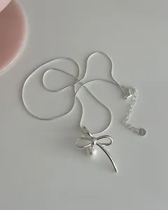 Detailed close-up of 925 sterling silver necklace with bow pendant and pearl drop