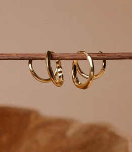 Minimalist gold plated hoop earrings displayed elegantly on a natural wooden branch