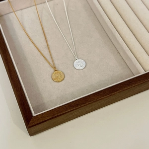 Detail of gold and silver coin pendants with Elizabeth II relief on a jewelry tray