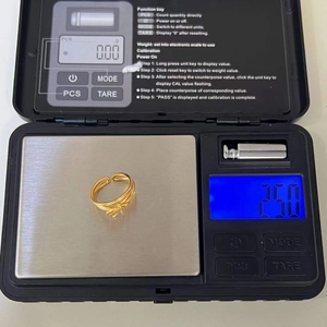 Macro shot of gold ribbon knot ring on digital scale showing precise 2.50g weight