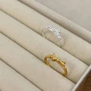 Eleganti anelli a fiocco in oro e argento, esposti in una scatola per gioielli in velluto
