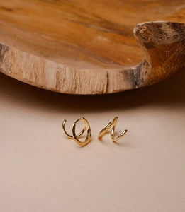 Close-up of golden geometric twisted spiral earrings with a polished mirror finish