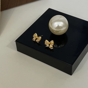 Elegant gold bow earrings with shimmering zircon pavé stones against a soft background