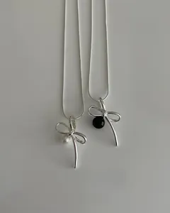 Detail showing two 925 silver bow necklaces with elegant pearl and black bead accents