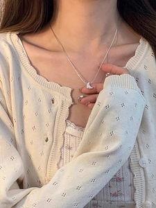 Détail du collier croissant en argent s925 sur mannequin en tricot de couleur crème