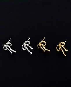 Close-up of gold and silver bow stud earrings with a polished metallic finish