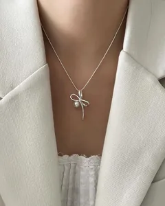 Close-up of elegant 925 silver bow necklace with pearl pendant on model neck