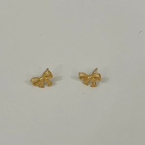 Detailed close-up of hollow gold bow earrings with intricate openwork metal textures