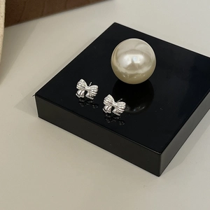 Elegant 925 silver bow stud earrings with sparkling zircon stones on a black mirror base