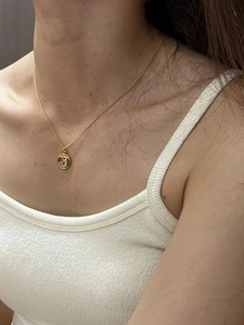Detail view of a French vintage gold coin pendant necklace worn on a woman's collarbone