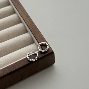 Minimalist S925 sterling silver twist hoop earrings with textured finish on wood base