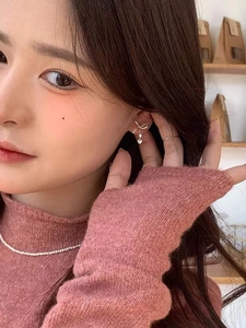Close-up of golden bow heart drop earrings with zircon on an elegant female model