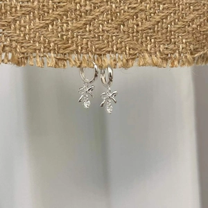 925 silver bow earrings with round loops and sparkling zircon charms on a textured fabric