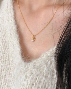Détail d'un collier en argent sterling 925 doré avec pendentif nœud et perle blanche