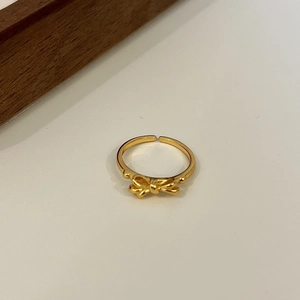 Dettaglio di un anello a fiocco dorato lucido con design aperto e regolabile