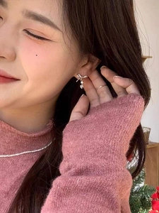 Detailed view of S925 silver bow stud earrings with heart charms on model ear