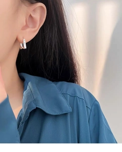 Close-up of minimalist S925 sterling silver square hoop earrings worn by a model