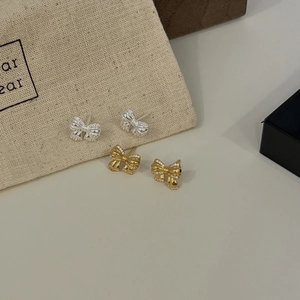 Close-up of elegant gold and silver 925 sterling silver bow earrings with woven texture