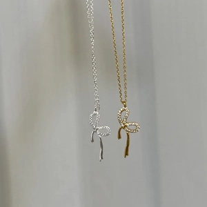 Dettaglio dei ciondoli a fiocco in argento e oro con pavé di cristalli lucidi