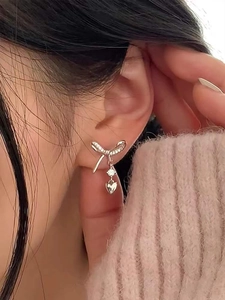 Close-up of S925 sterling silver bow and heart zircon stud earrings worn by a model