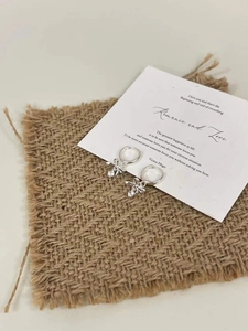 Detailed view of 925 sterling silver bow earrings with sparkling zircon on linen