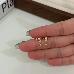 Gros plan montrant la taille des boucles d'oreilles nœud doré avec zircons brillants