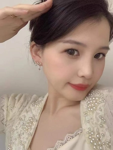 Close-up of bow-shaped rose gold earrings with zircon pendants worn by a model