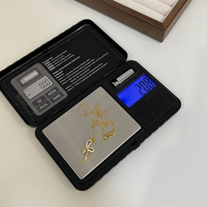 Dettaglio di una collana in argento S925 dorato con ciondolo a fiocco e strass su bilancia