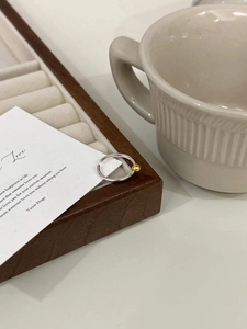 Détail de la bague ajustable en argent 925 avec perle bicolore dorée sur plateau en bois
