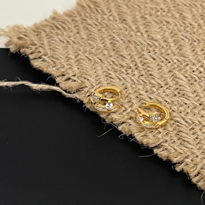 Macro detail of gold-plated 925 silver huggie earrings with sparkling zircon star motifs