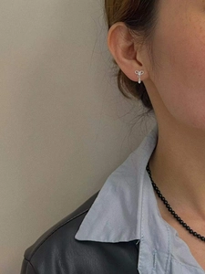 Gros plan d'une boucle d'oreille nœud en argent avec pendentif zircon portée par un mannequin