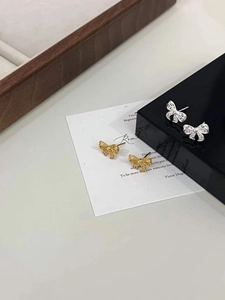 Detailed shot of hollow woven bow earrings in polished gold and silver finishes
