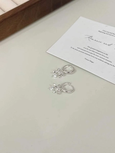 Detail of 925 sterling silver bow earrings featuring a zircon drop charm on a hoop