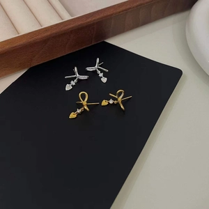 Close-up of bow knot earrings with sparkling heart-shaped cubic zirconia in gold and silver