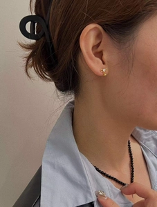 Détail de boucles d'oreilles cœur et clé dorées avec diamants sur un mannequin