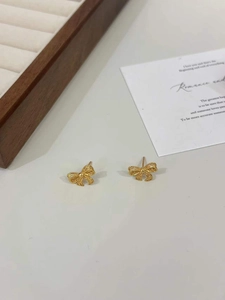 Detailed macro shot of gold hollow bow earrings with woven texture on a card