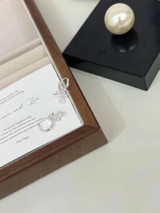Macro detail of silver bow earrings with zircon stones on a white background card
