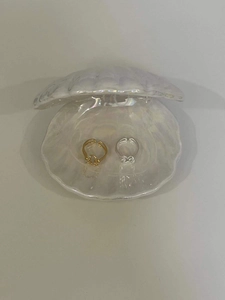 Detailed view of gold and silver bow-knot rings displayed on a white shell tray