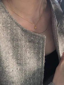 Detailaufnahme einer zarten goldenen Herzanhänger-Halskette an einer klassischen Kette