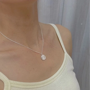 French vintage silver oval coin pendant necklace shown on a model neck with fine chain