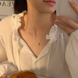 Élégant collier croissant en argent sterling S925 doré porté sur un haut plissé blanc