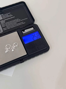 Detail shot showing 925 sterling silver bow earrings weighing 2.58g on a digital scale