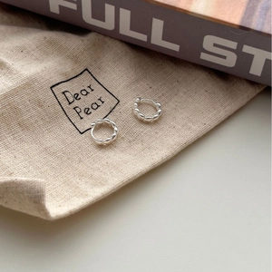 Pair of S925 sterling silver hoop earrings with heart-shaped textures on linen bag